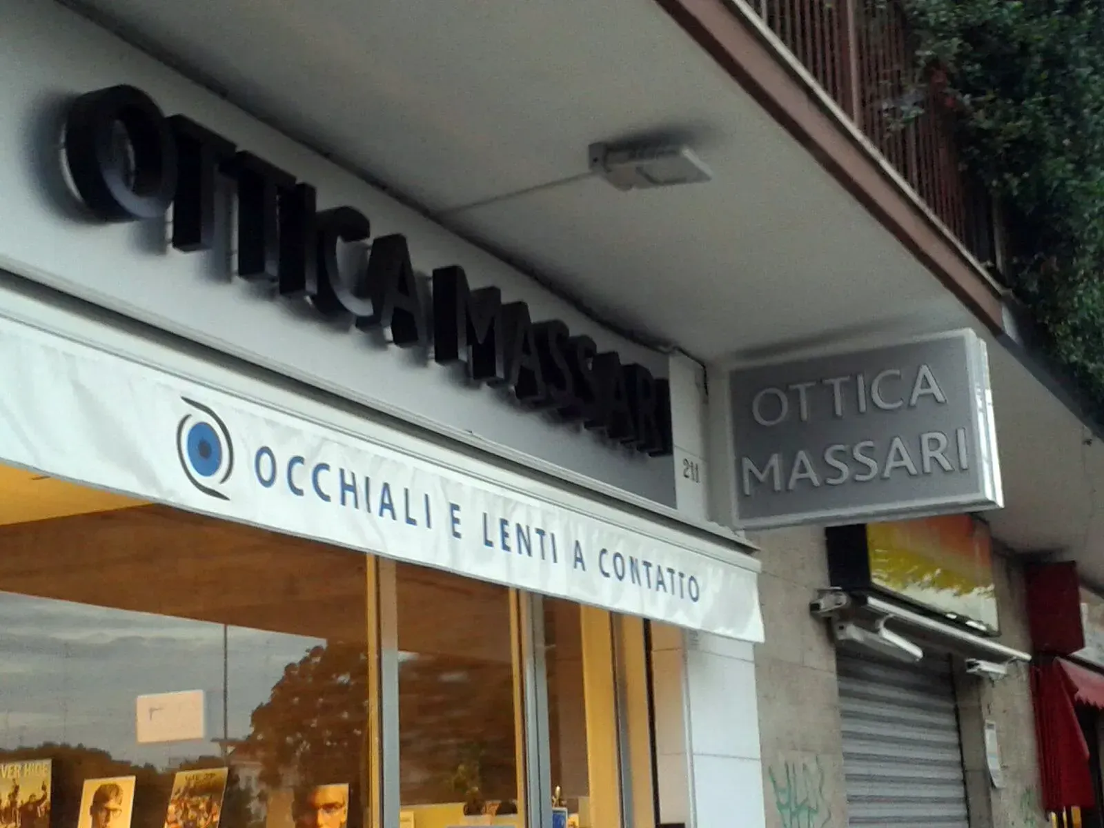 Optician storefront with “Ottica Massari” sign and “Occhiale, lenti e contatto” banner