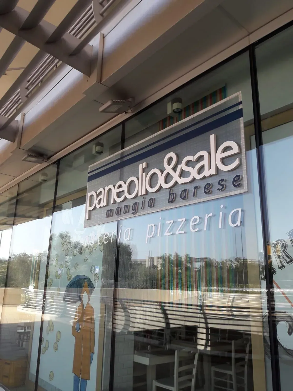 Vetrina con insegne “paneolio&sale” e “pizzeria”, che richiama l’area del patio esterno.