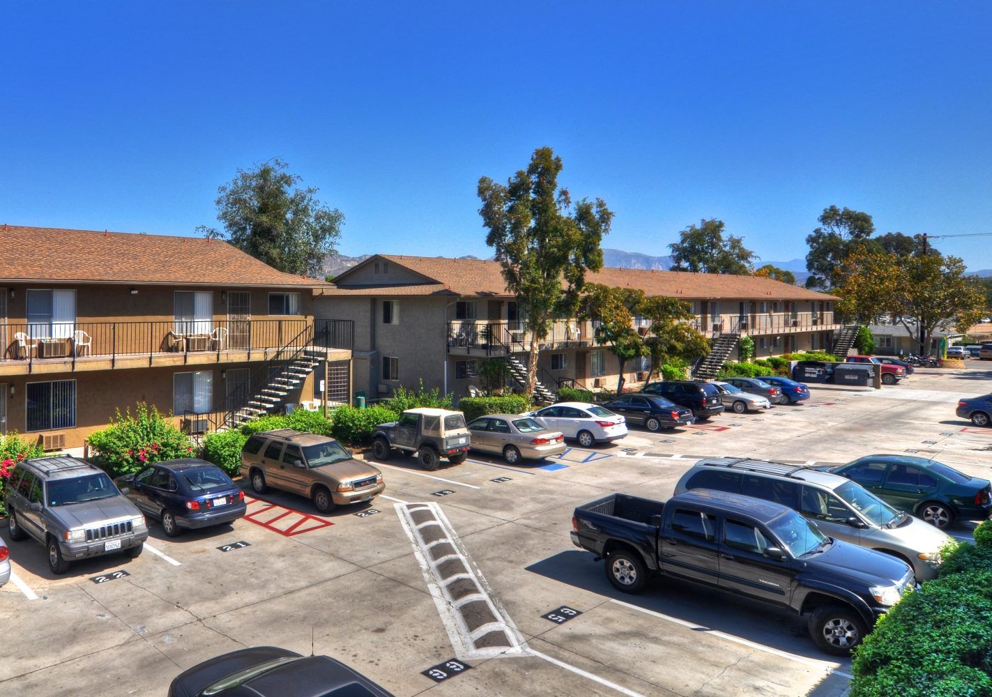 Apartment complex parking lot with cars under a clear blue sky