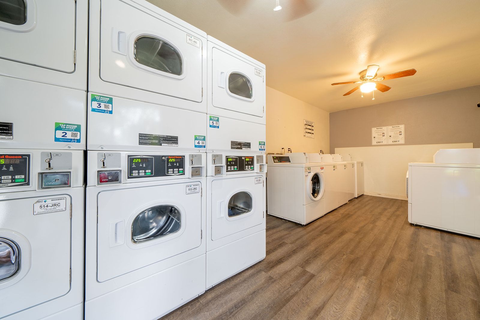 Bright laundromat with stacked washers and dryers and wood-look flooring