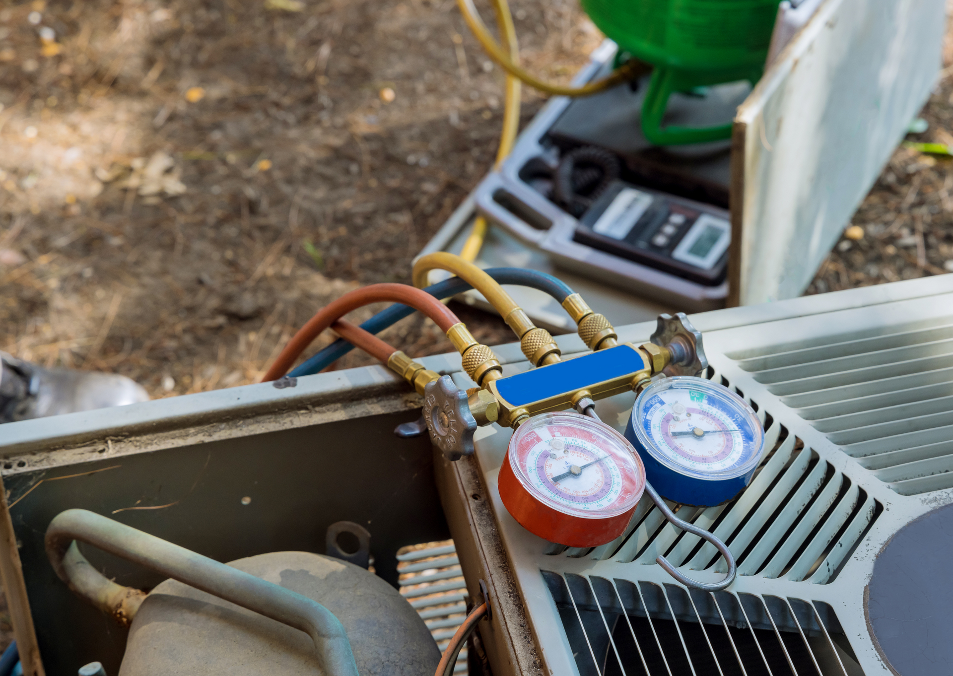 HVAC repair with gauges connected to an air conditioning unit for testing.