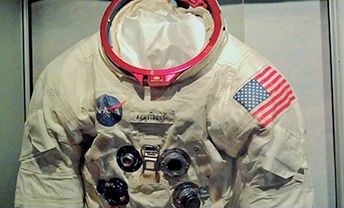 A NASA space suit is displayed in a glass case