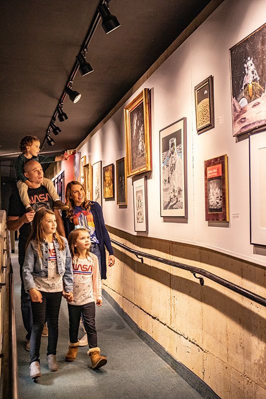 A family is walking down a hallway in the museum looking at photos and prints.