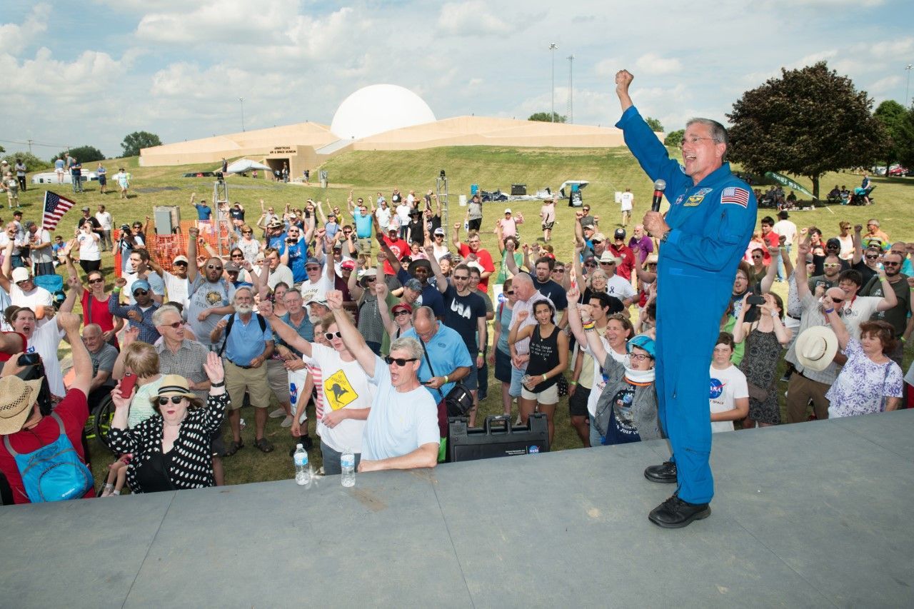 Don Thomas in a flight suit is standing in front of a crowd of people