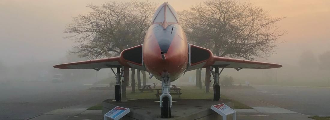 A NASA jet is parked in the fog in front of the Armstrong Air & Space Museum.