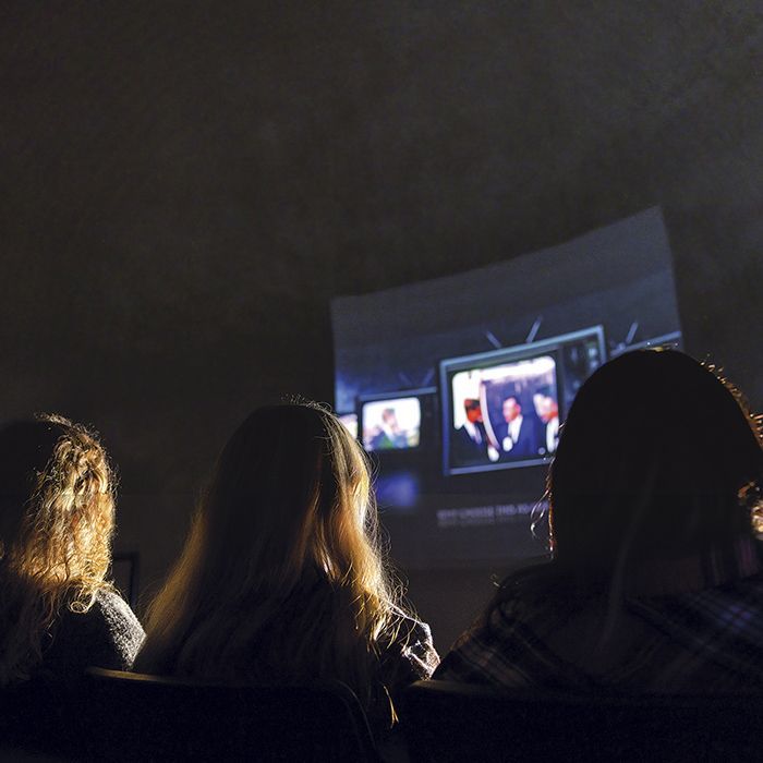 A group of people are watching a movie on a large screen in the Armstrong Theater.