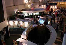 A group of people are standing in a room with a large hole in the middle. It is the National Aviation Hall of Fame.