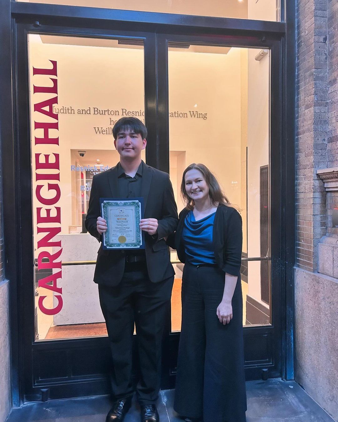 A woman standing next to a man that is holding a certificate.