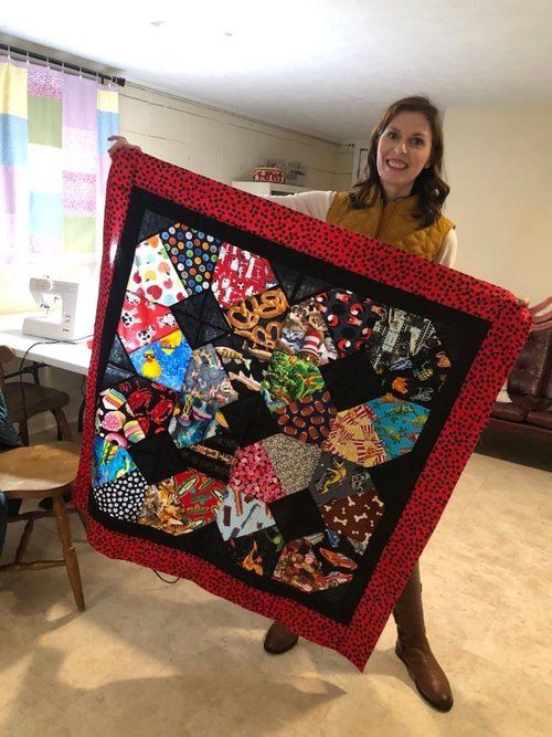 A woman is holding a quilt in her hands in a room.