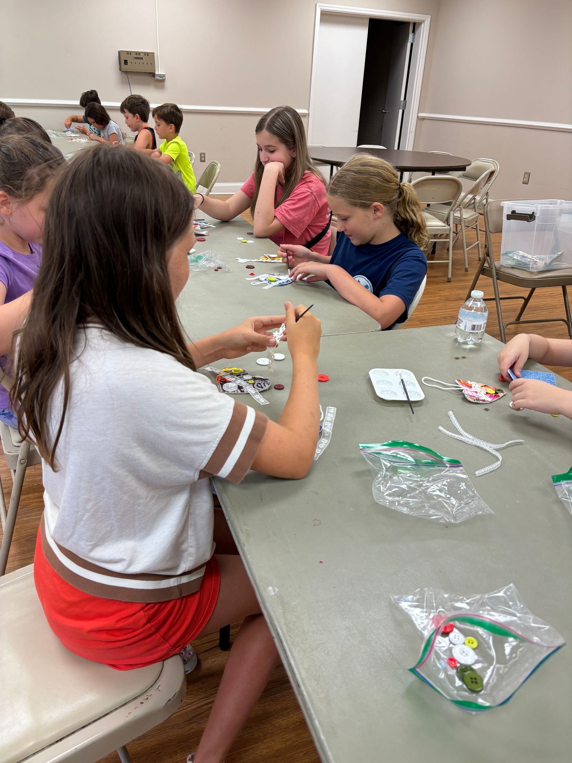 A group of children are sitting at a table making crafts.