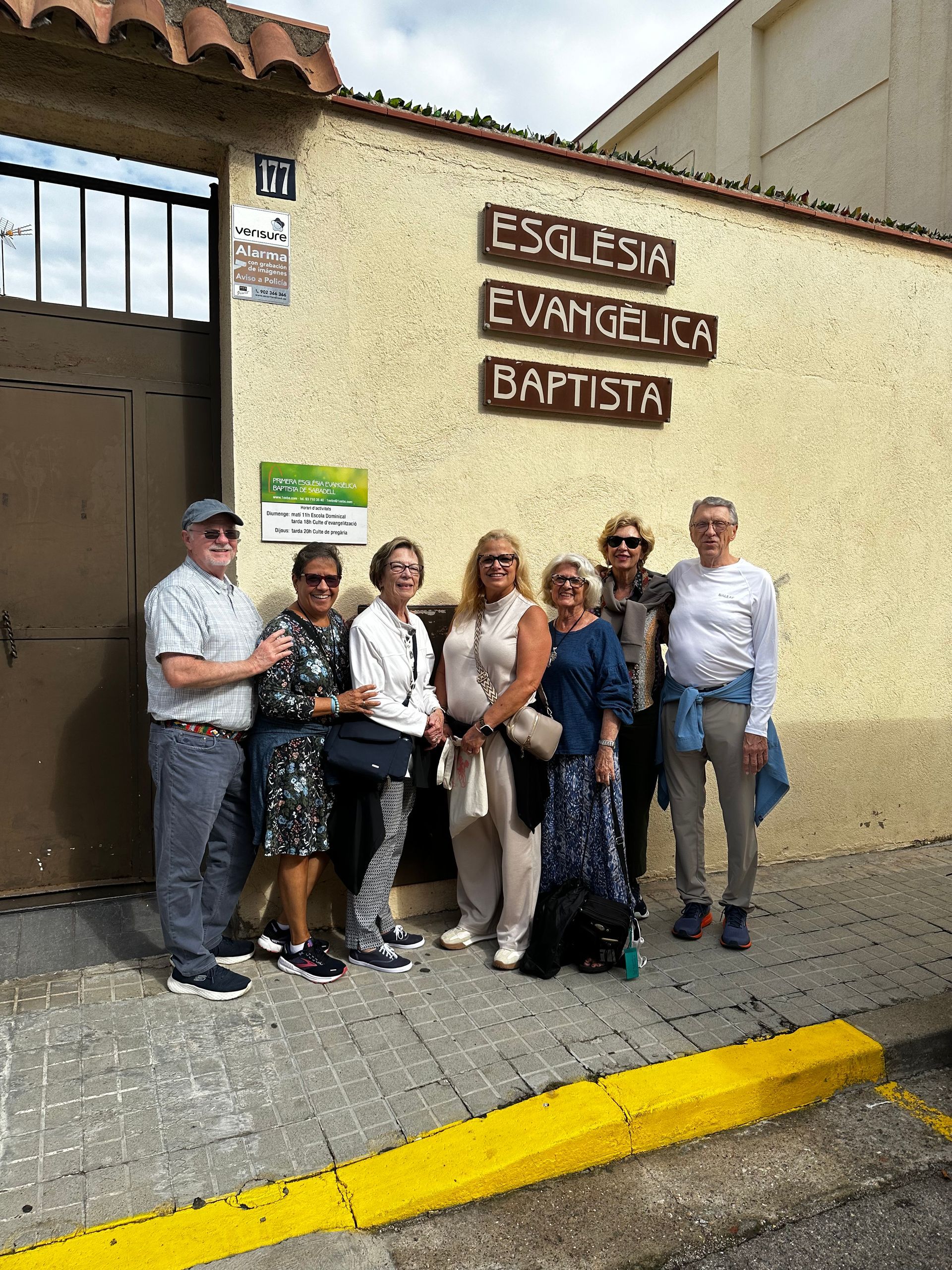 A group of 7 people are standing in front of a building in Spain.