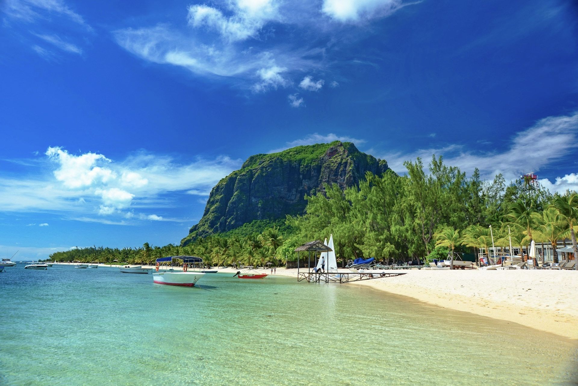 Beach scene with Le Morne mountain in Mauritius under a blue sky.
