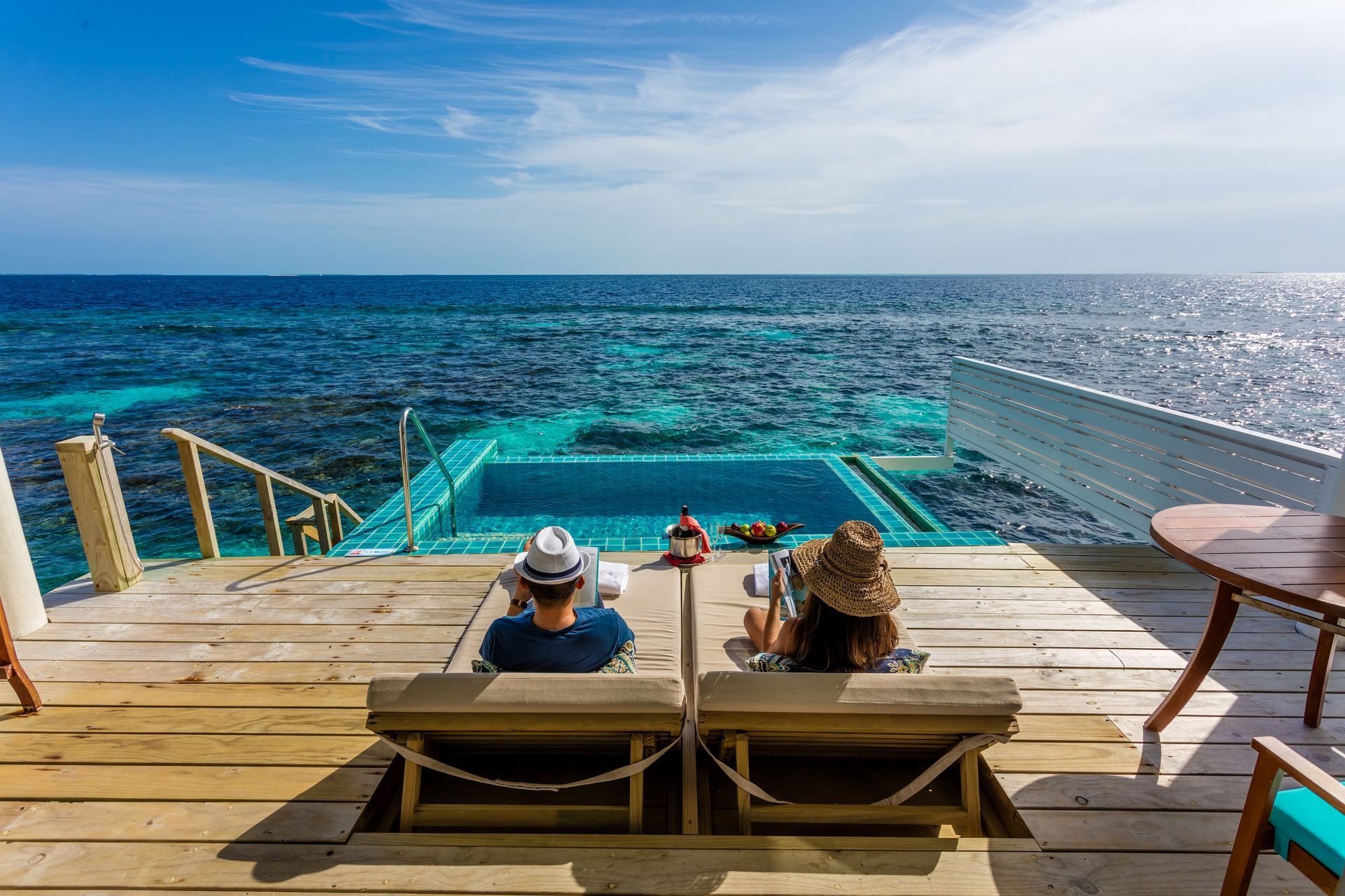 Couple relaxing on deck with ocean view and infinity pool.