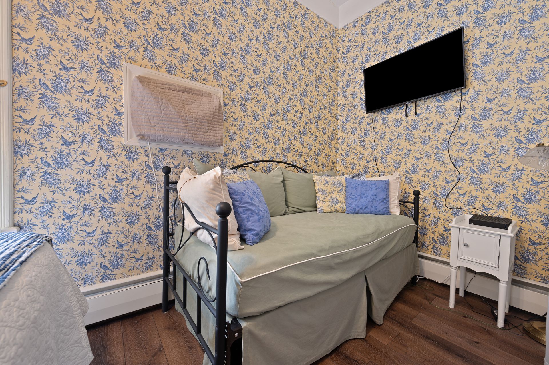 A bedroom with a day bed and a flat screen tv on the wall.