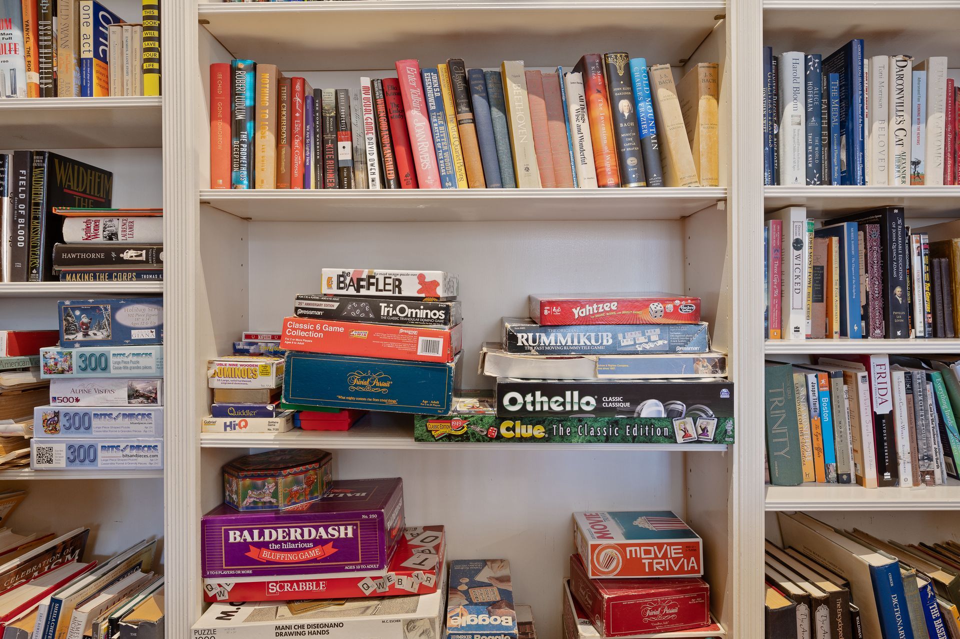 A bookshelf filled with books and a stack of board games.