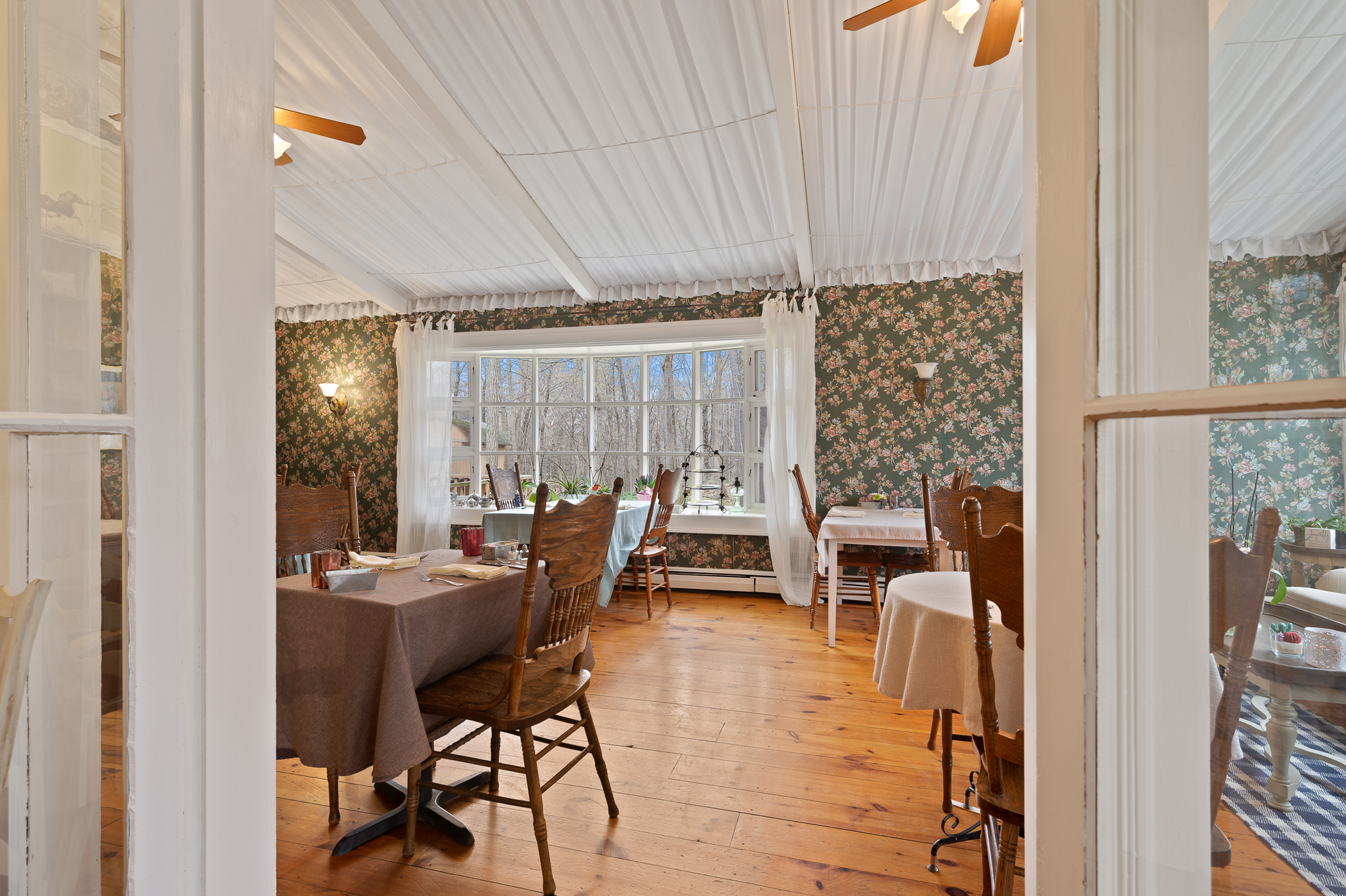 A dining room with tables and chairs and a ceiling fan.