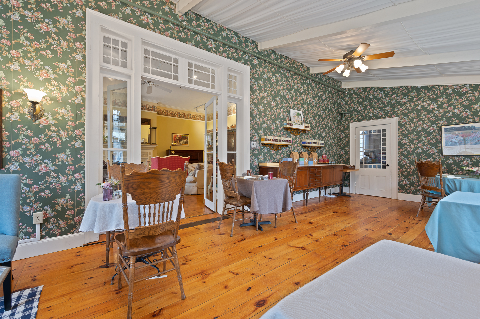 A dining room with tables and chairs and a ceiling fan.