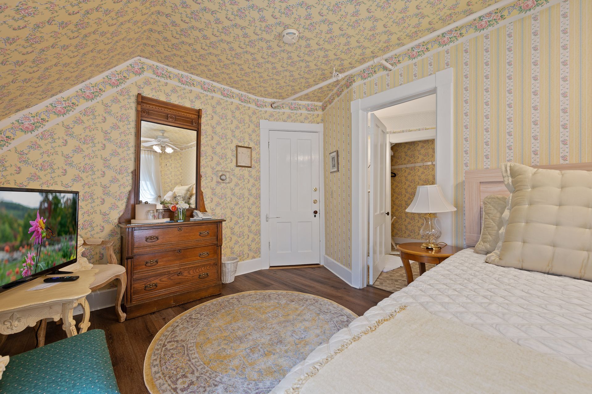 A bedroom with a bed , dresser , mirror and television.