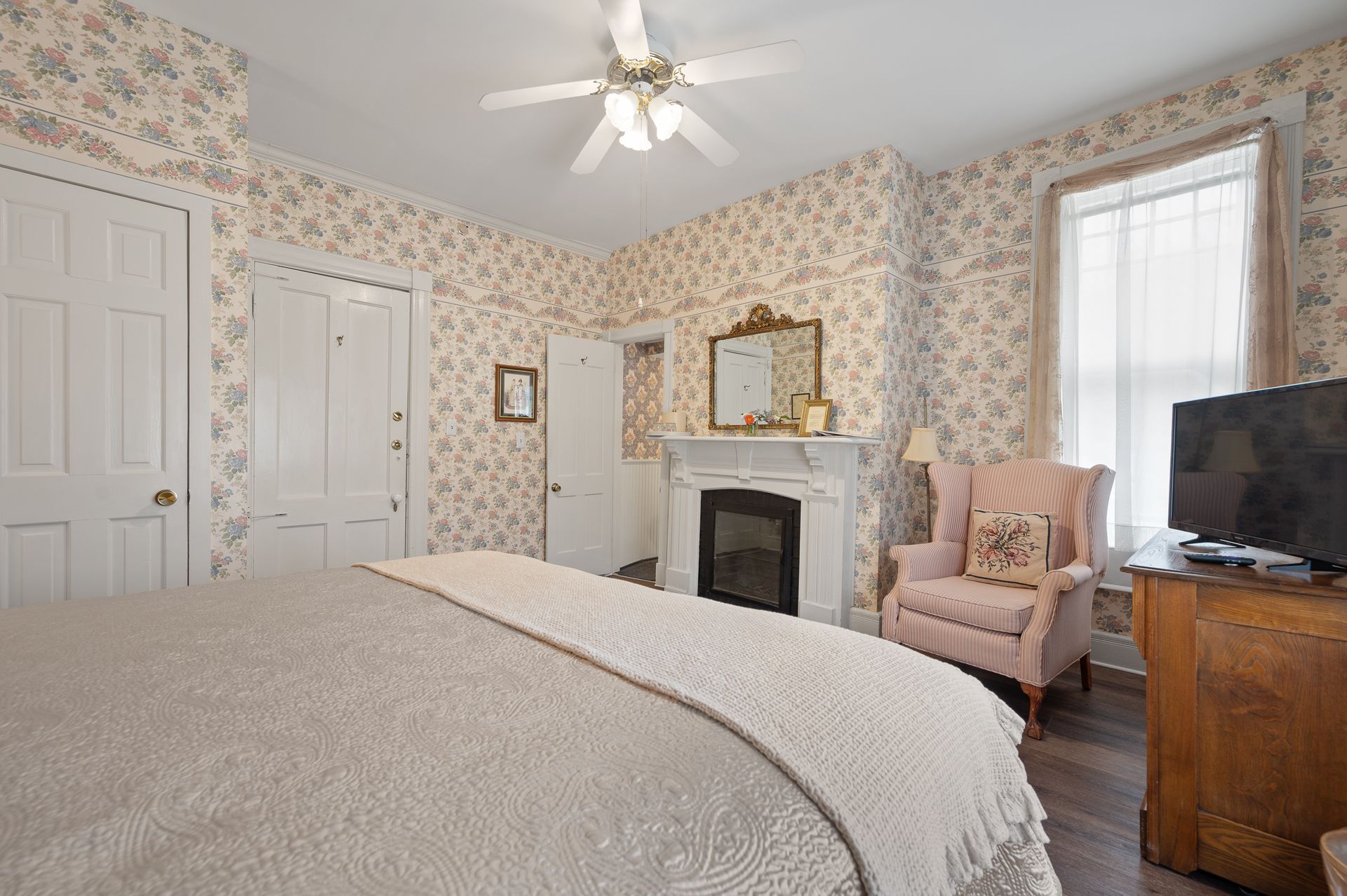 A bedroom with a bed , chair , fireplace and television.