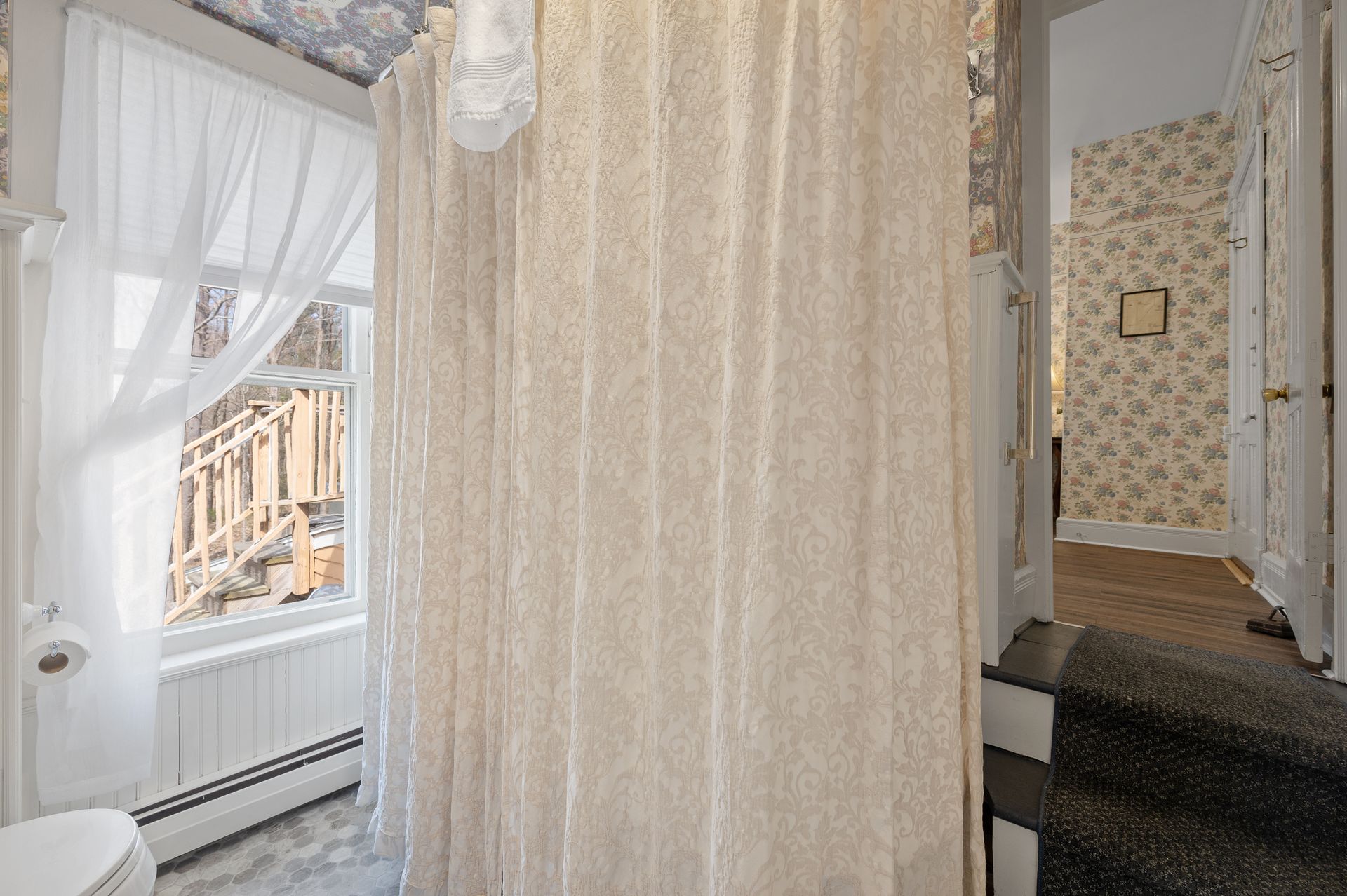 A bathroom with a shower curtain and a window.