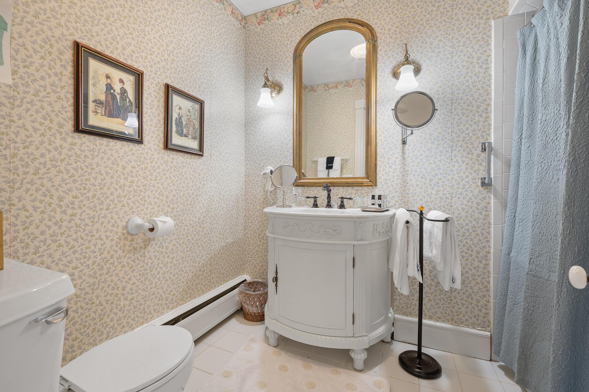 A bathroom with a toilet , sink , mirror and shower curtain.