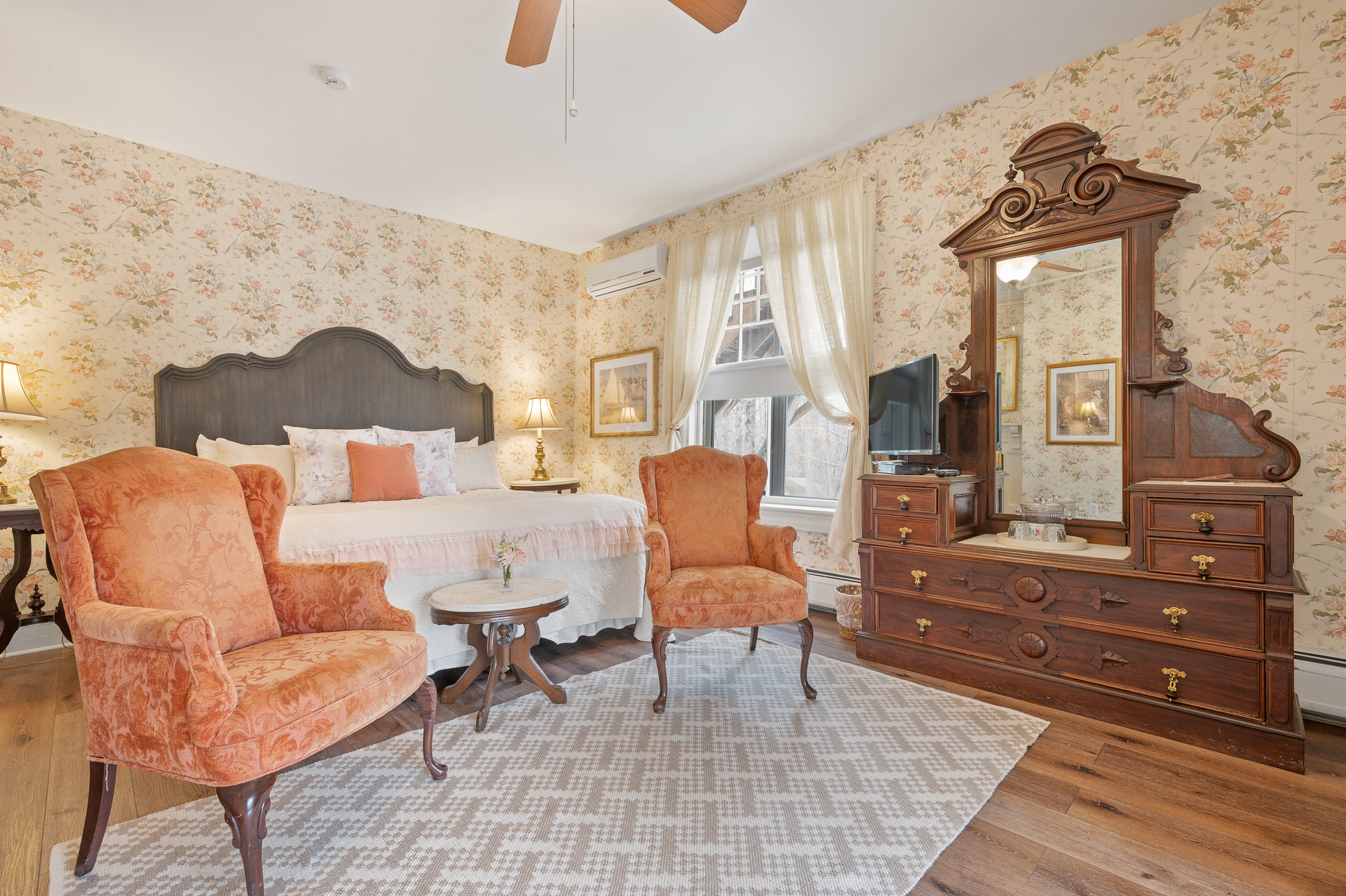 A bedroom with a bed , chairs , dresser and mirror.