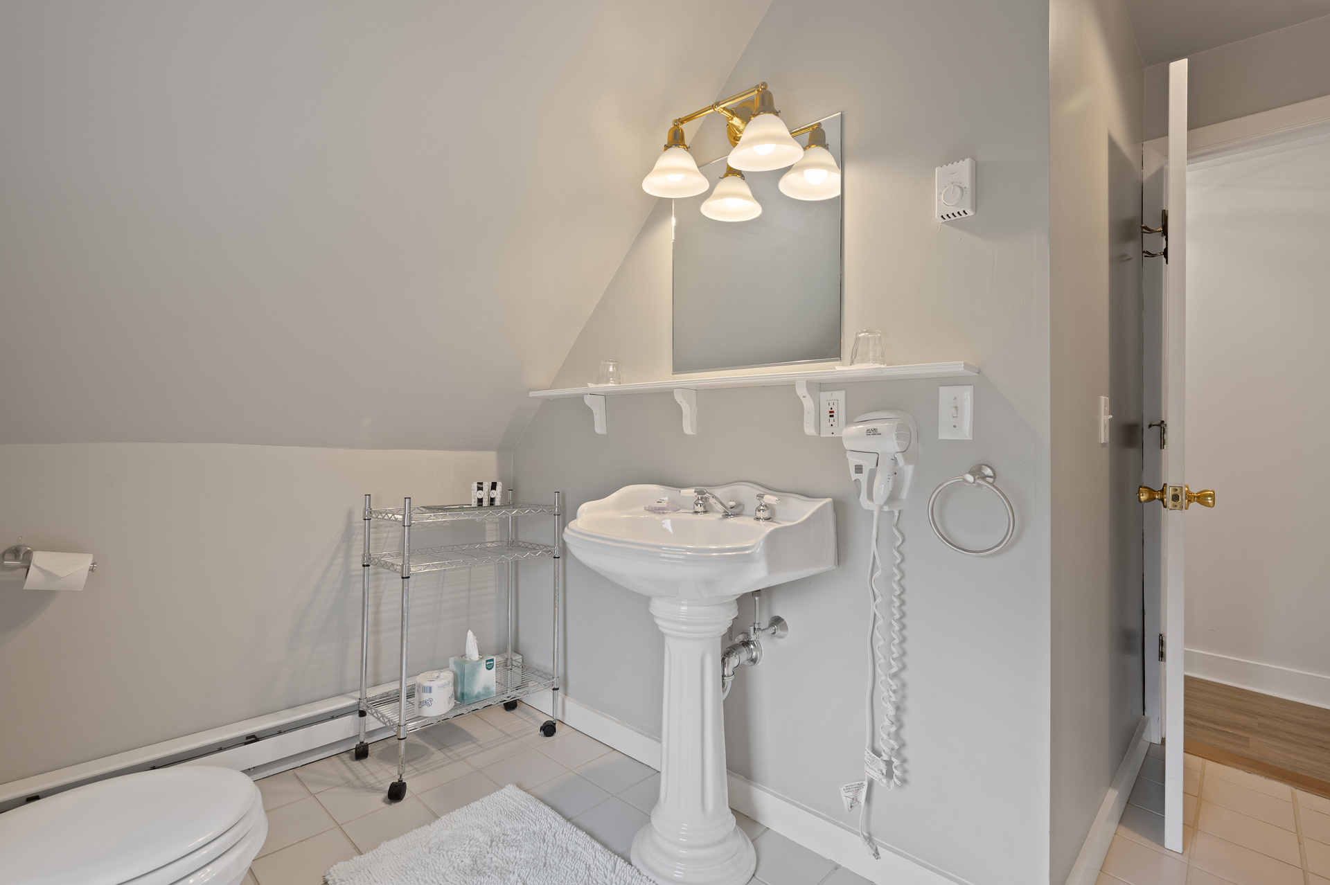 A bathroom with a toilet , sink , mirror and dryer.