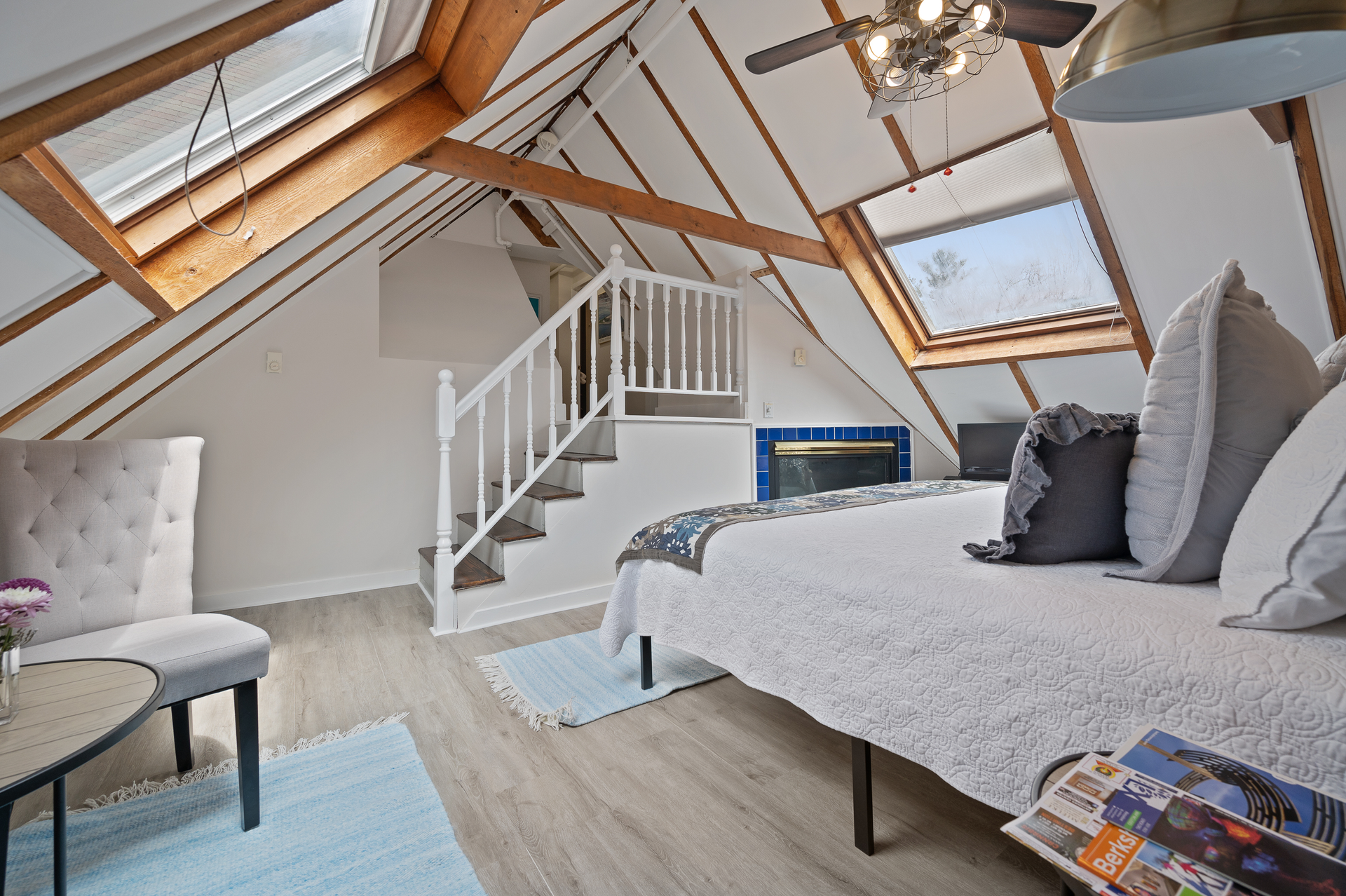 A bedroom with a bed , chair , table and stairs.