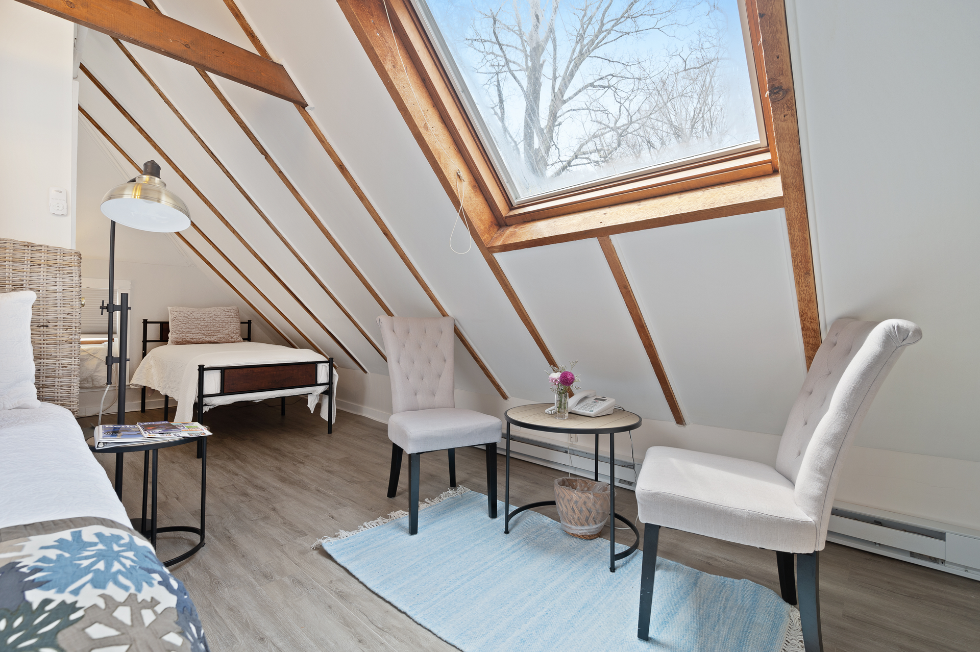 A bedroom with a bed , chairs , a table and a skylight.