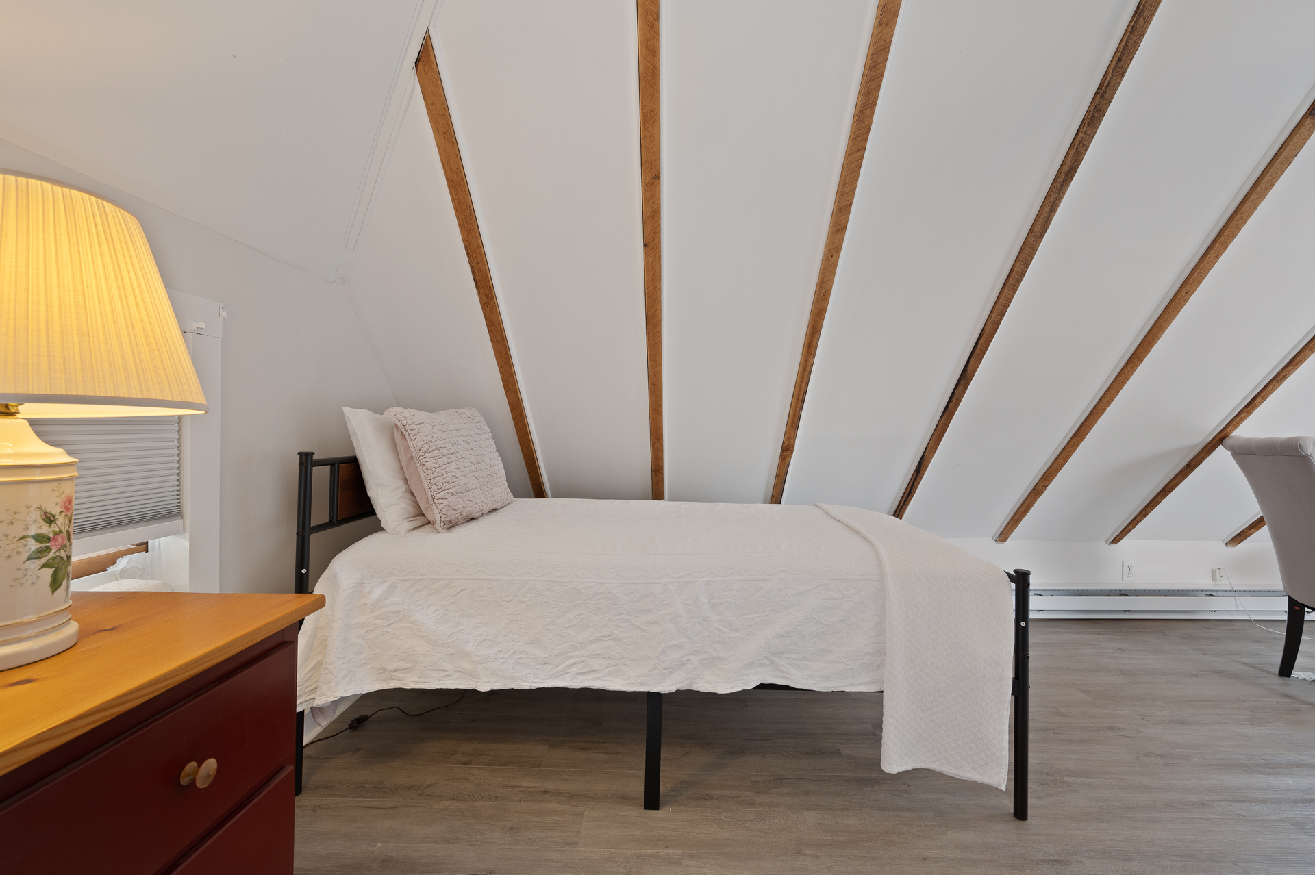 A bedroom with a single bed and a lamp