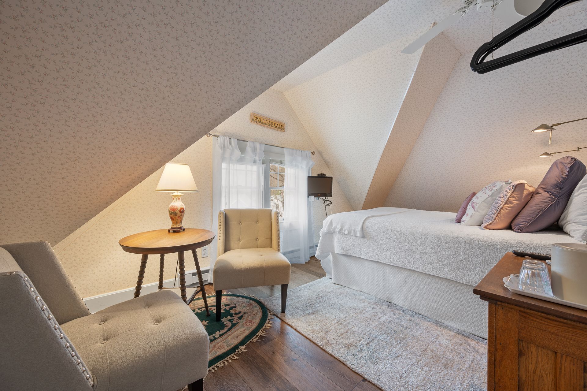 A bedroom with a bed , chair , table and lamp.