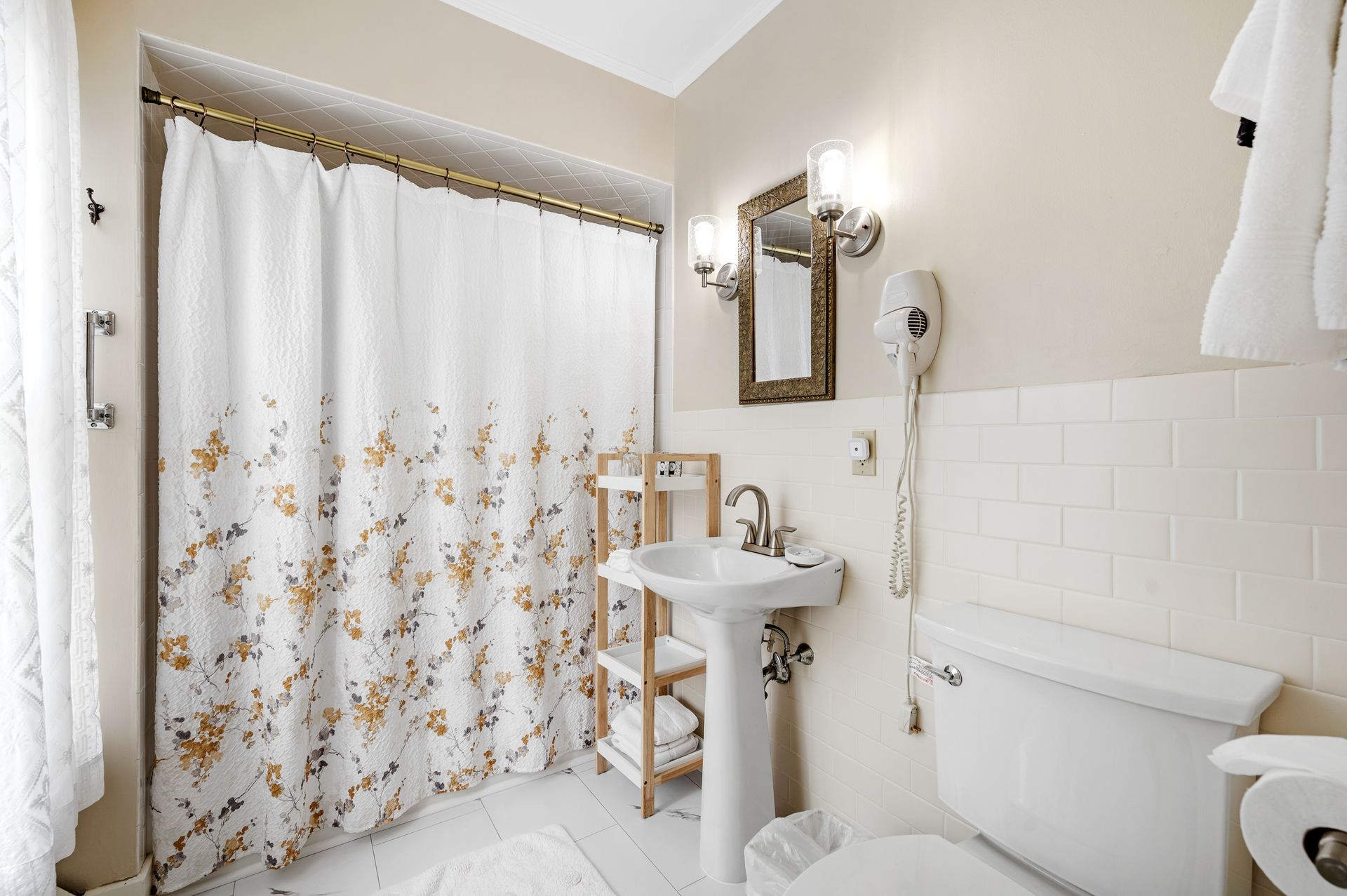 A bathroom with a sink , toilet , mirror and shower curtain.