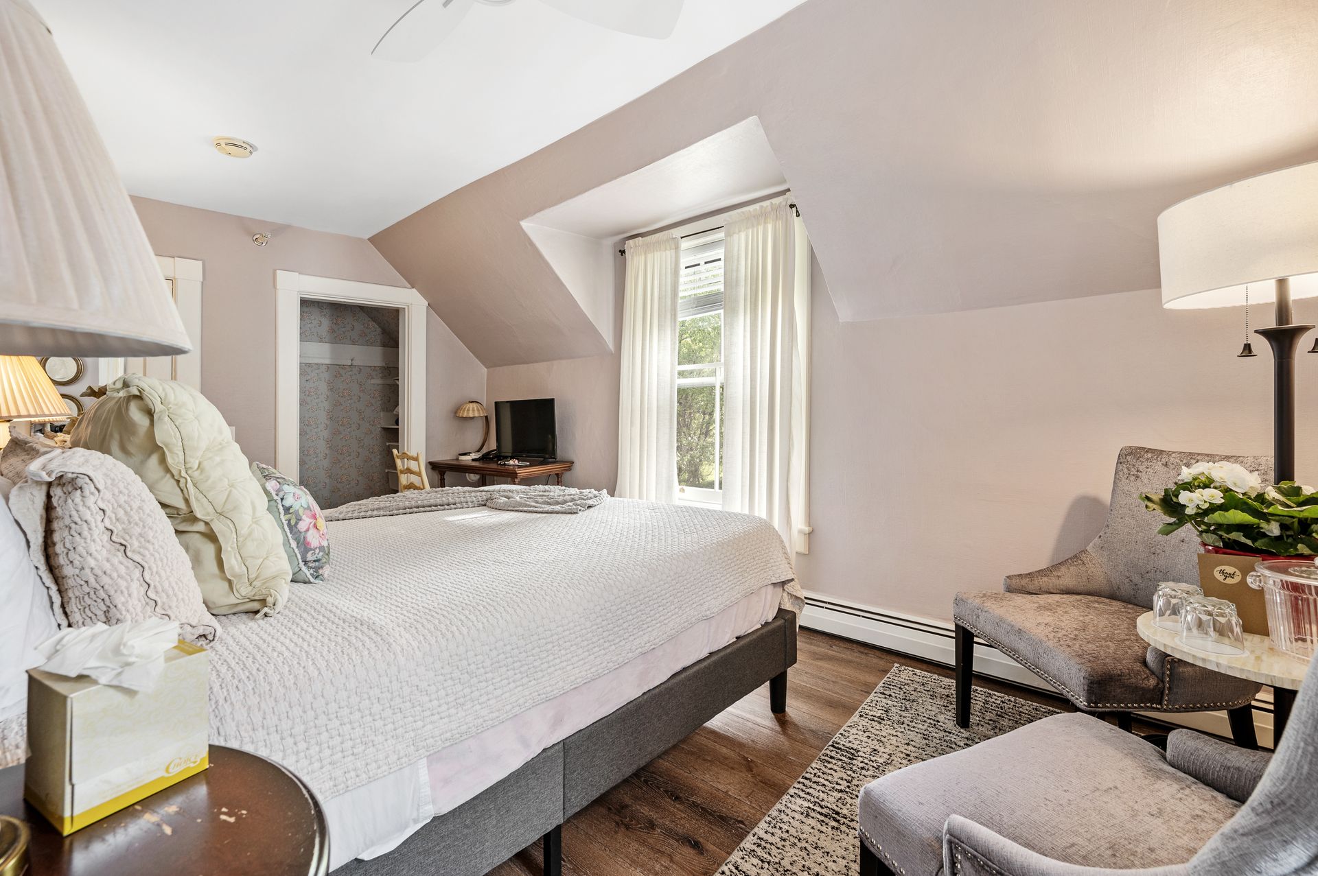A bedroom with a large bed , chair , lamp and ottoman.