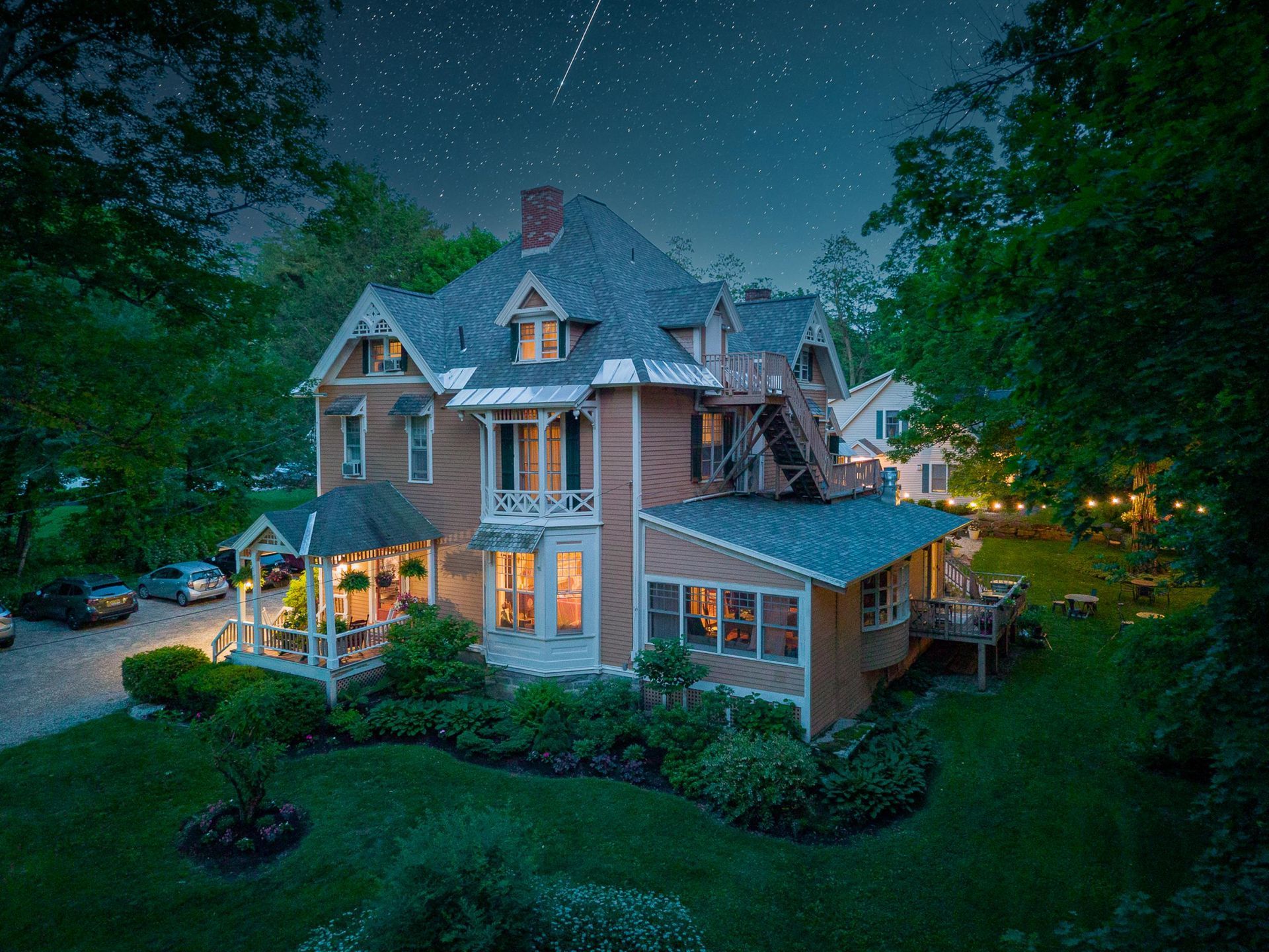 An aerial view of a large house at night with cars parked in front of it.