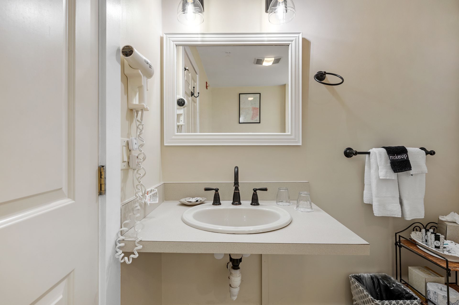 A bathroom with a sink , mirror and hair dryer.