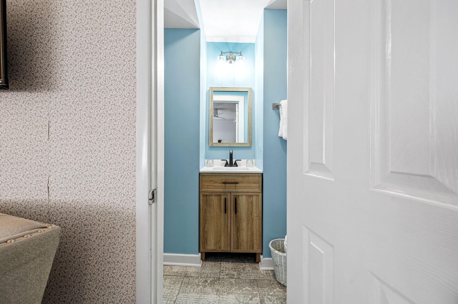 A bathroom with a sink , mirror , and blue walls.