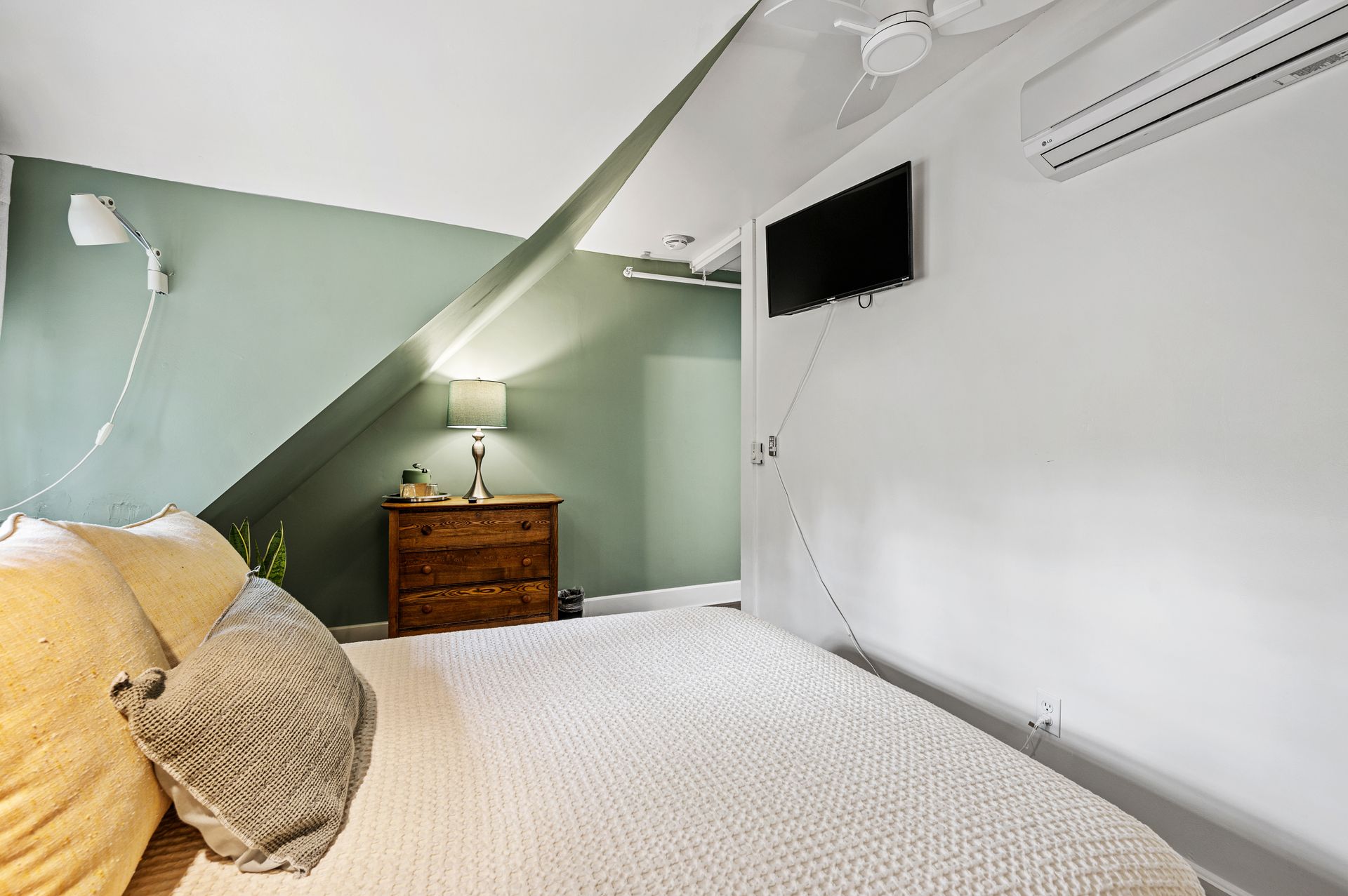 A bedroom with a bed , dresser , and television.