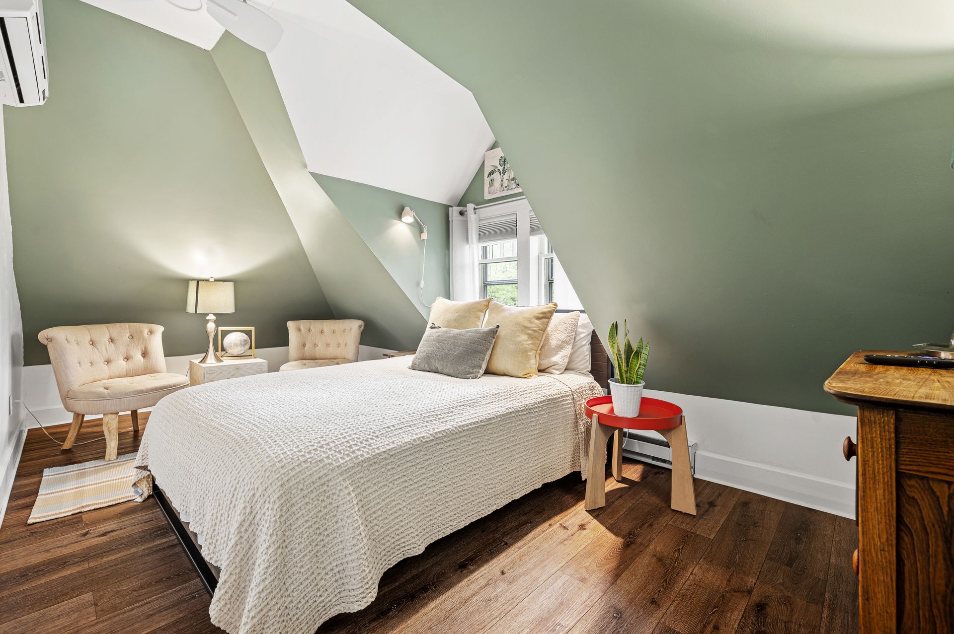 A bedroom with a bed , chairs , and a dresser.