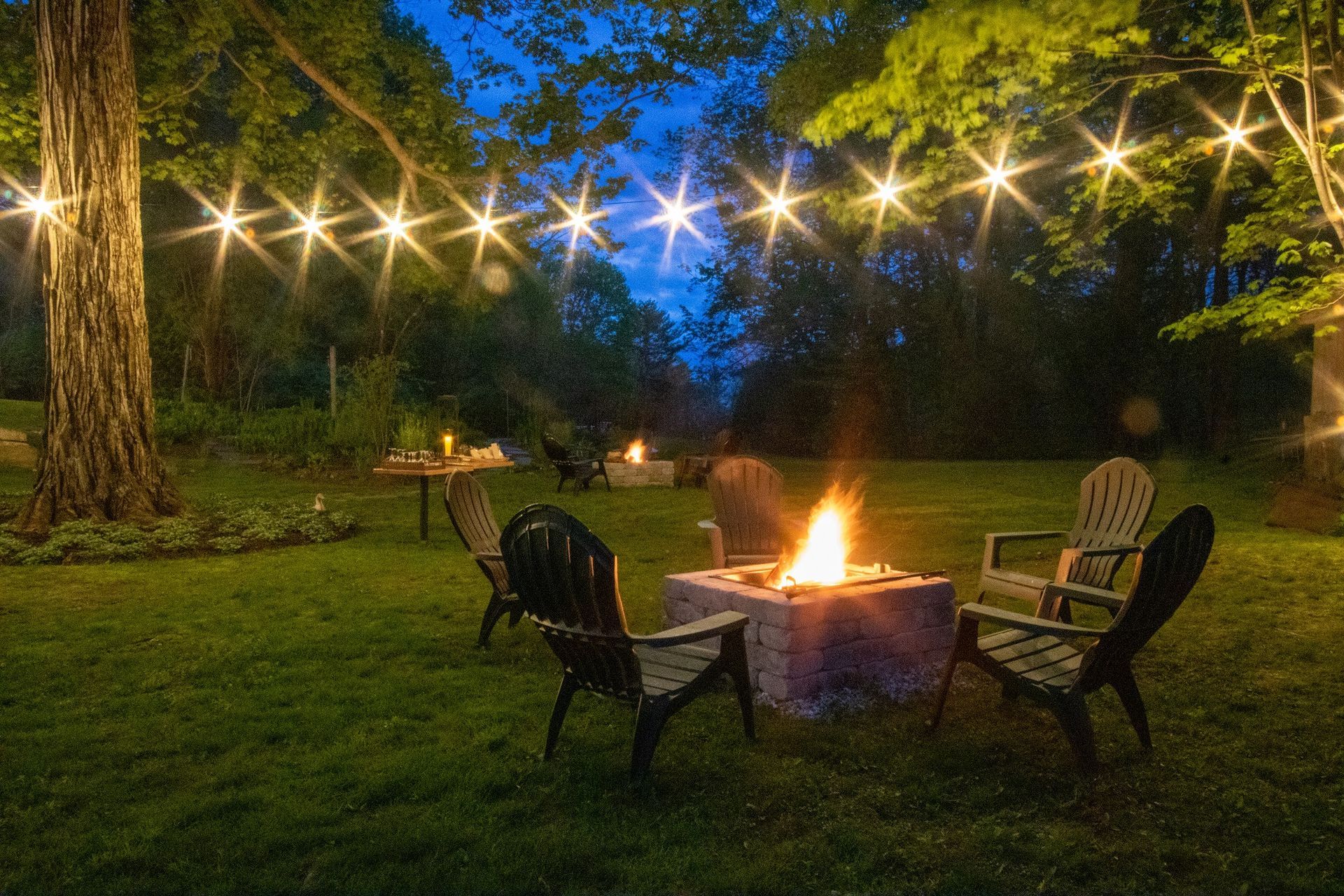 A fire pit with chairs around it is lit up at night.