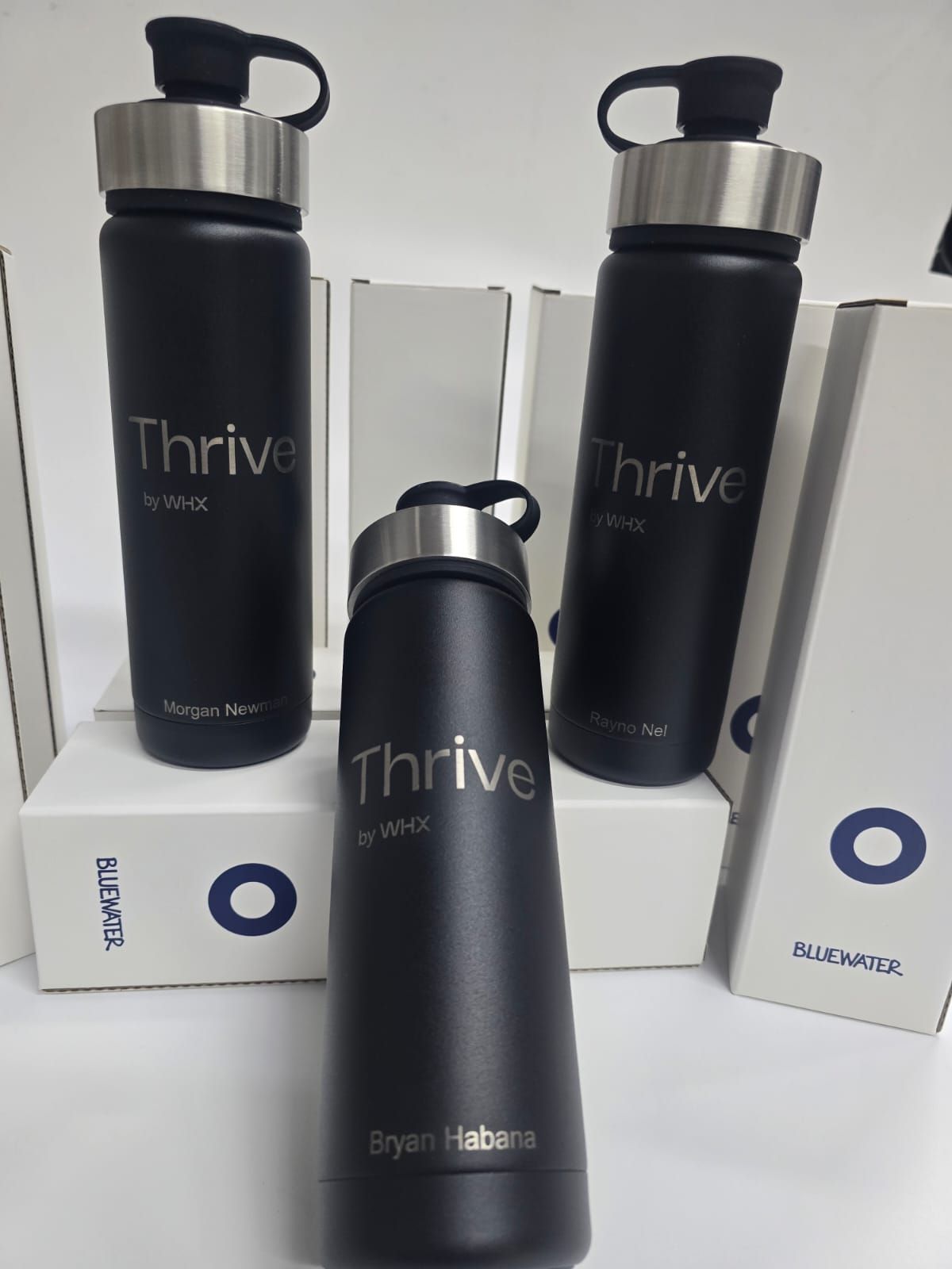 Three black water bottles with silver lids and 