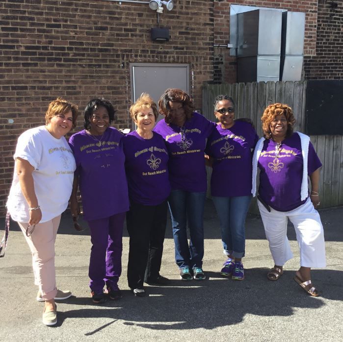 A group of women are posing for a picture and one of them has a purple shirt on