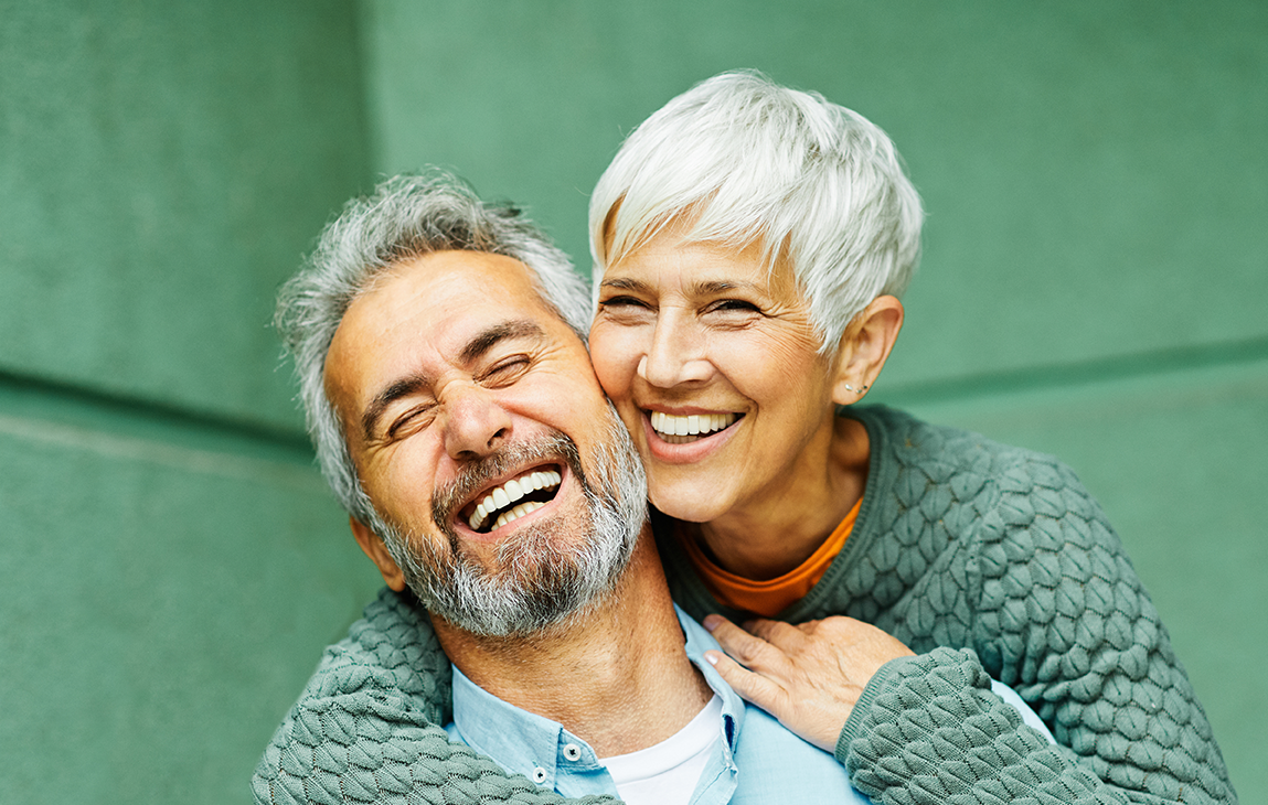 A man and a woman are laughing and hugging each other.