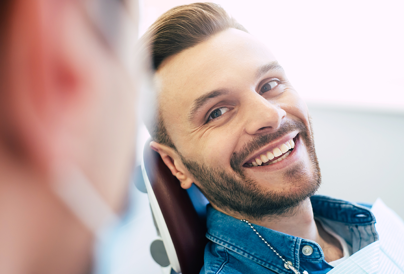 A man is smiling while sitting in a dental chair.