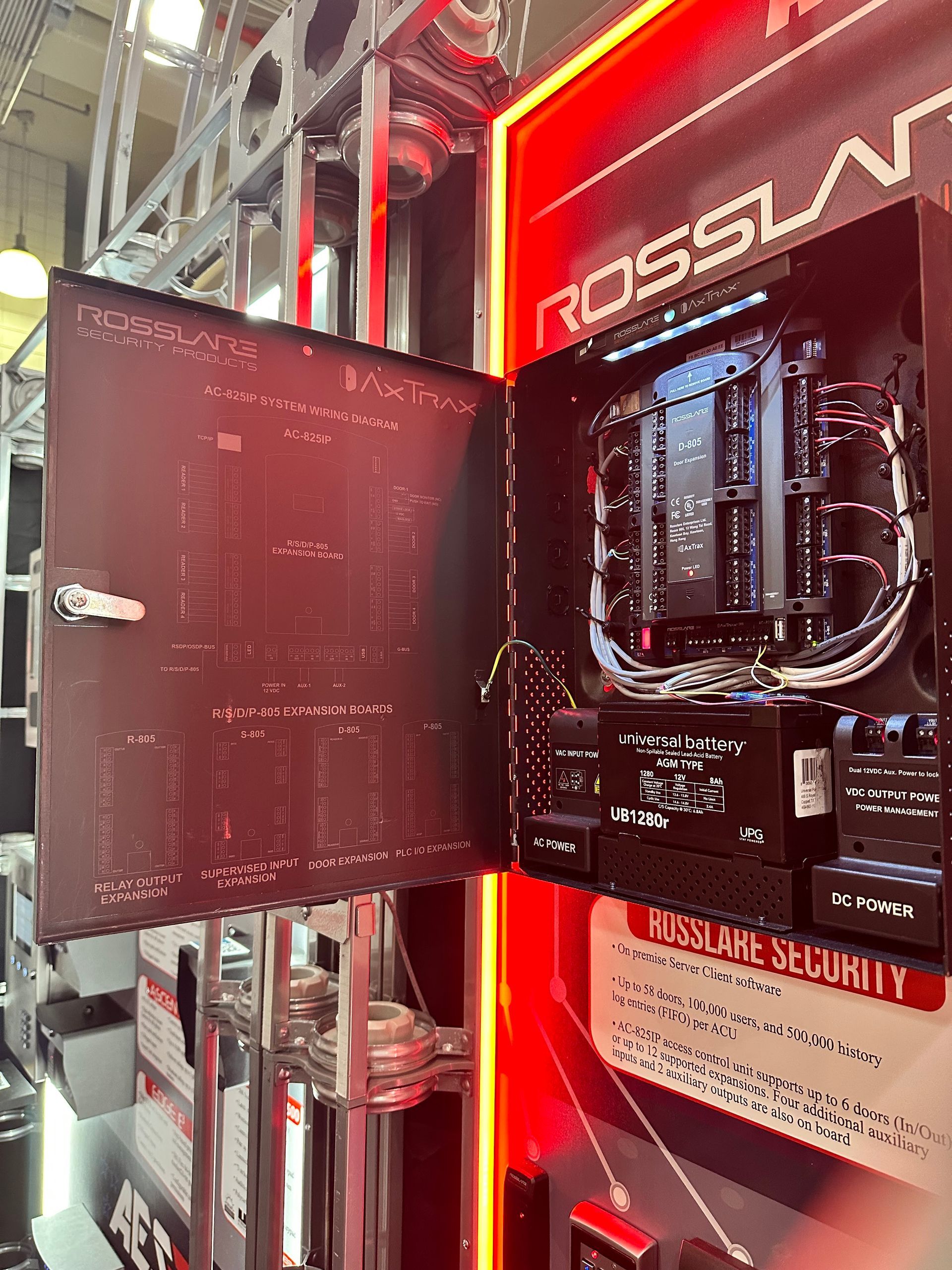 Opened black security system cabinet with wiring and components, mounted on a wall with red accents.