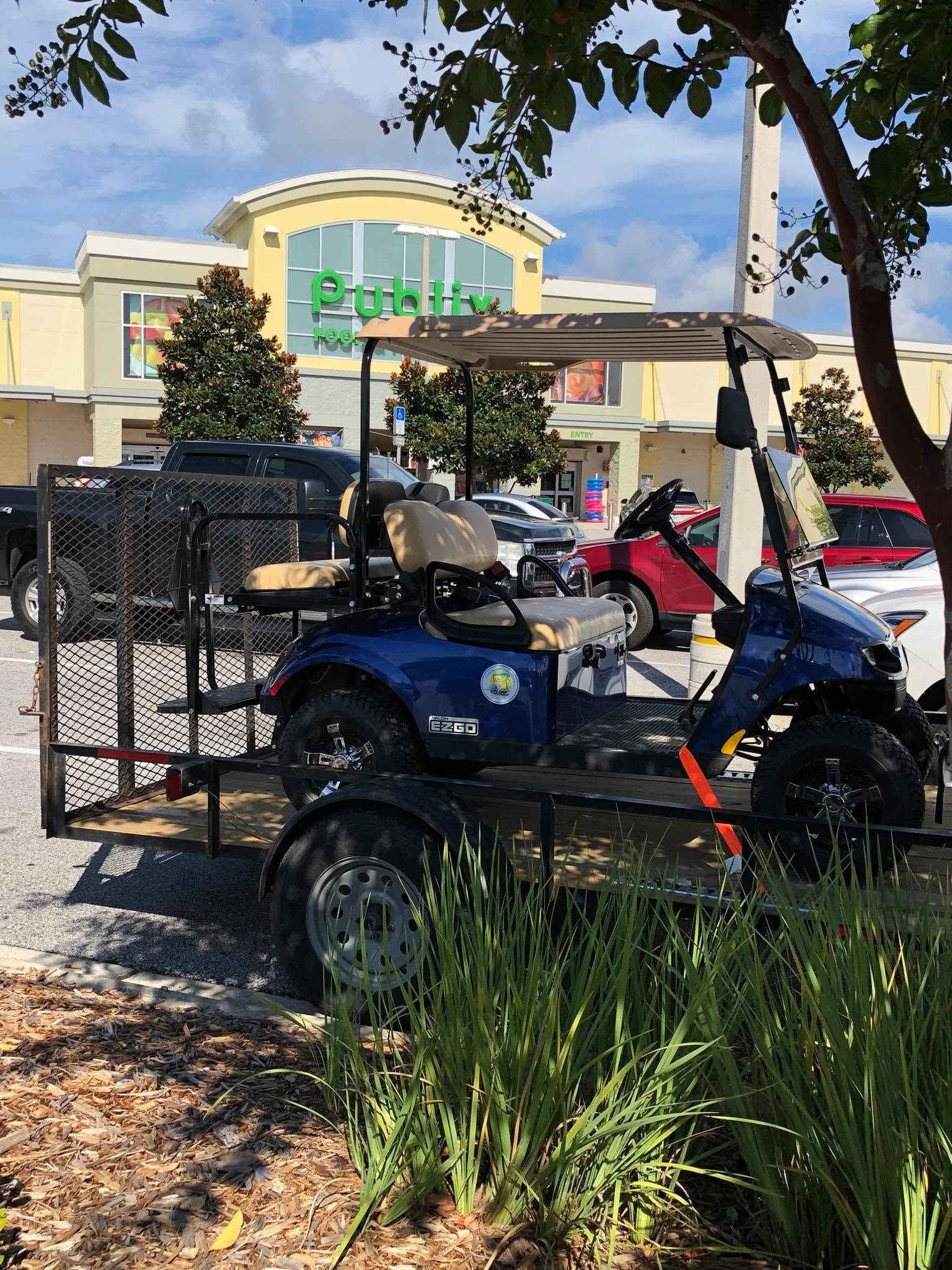 Blue mobility scooter with cargo basket parked outside a storefront under trees