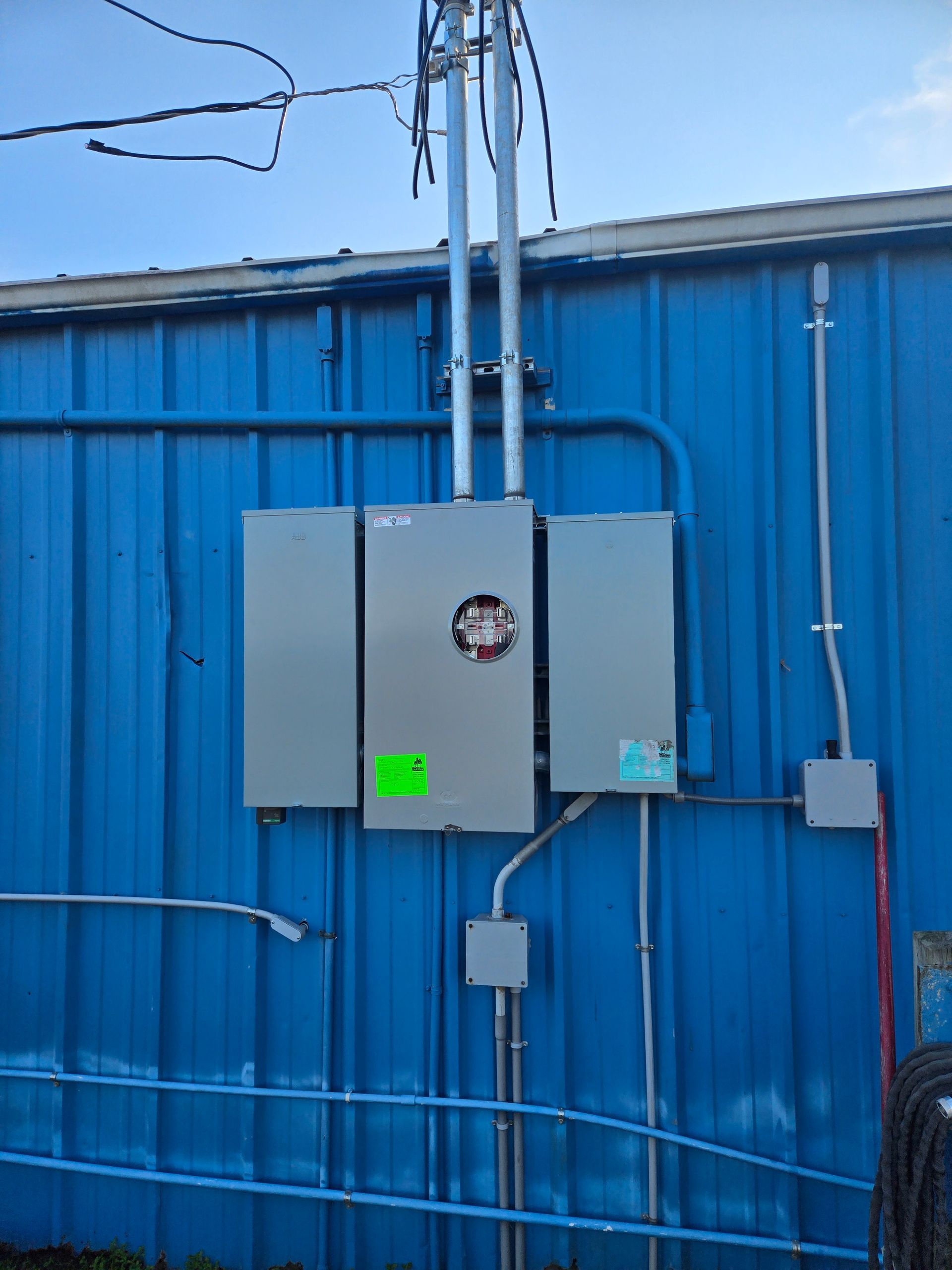 Blue metal building wall with electrical control boxes and conduit mounted outside