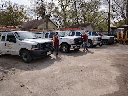 Several white utility trucks parked in a lot with two people standing nearby.