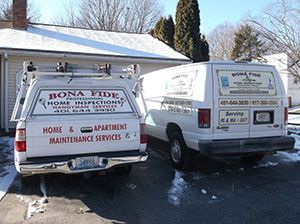 Two vans parked in front of a house, surrounded by a blanket of snow covering the ground.