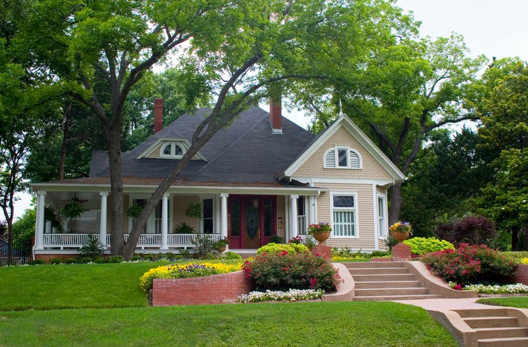 A large house featuring a welcoming front porch and a well-maintained front yard.