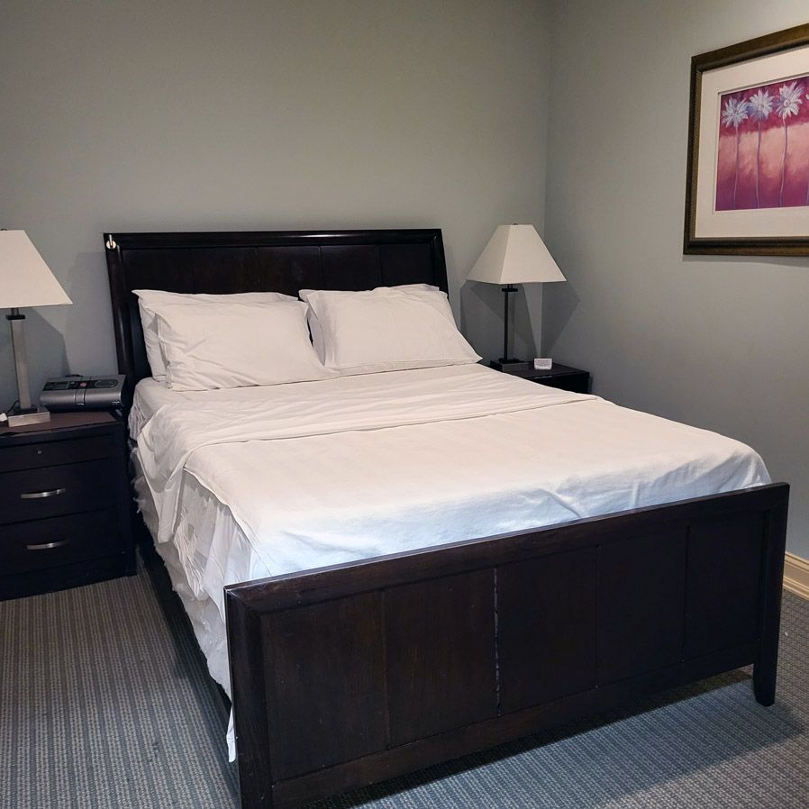 A bedroom with a picture on the wall above the bed